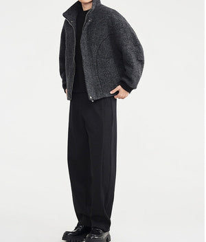 Person wearing a gray coat and black pants on a white background