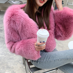 Person wearing a pink fluffy coat holding a coffee cup indoors.