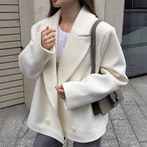 Person wearing a white blazer with a neutral background