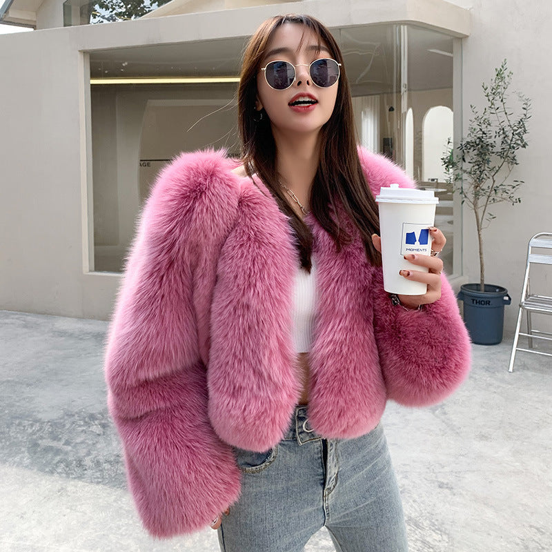 Woman wearing a pink fur coat holding a cup outdoors.