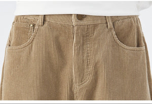 Close-up of beige corduroy pants with a white shirt underneath on a light gray background.