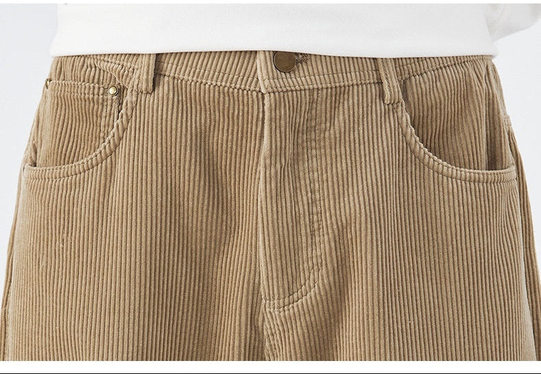 Close-up of beige corduroy pants with a white shirt underneath on a light gray background.