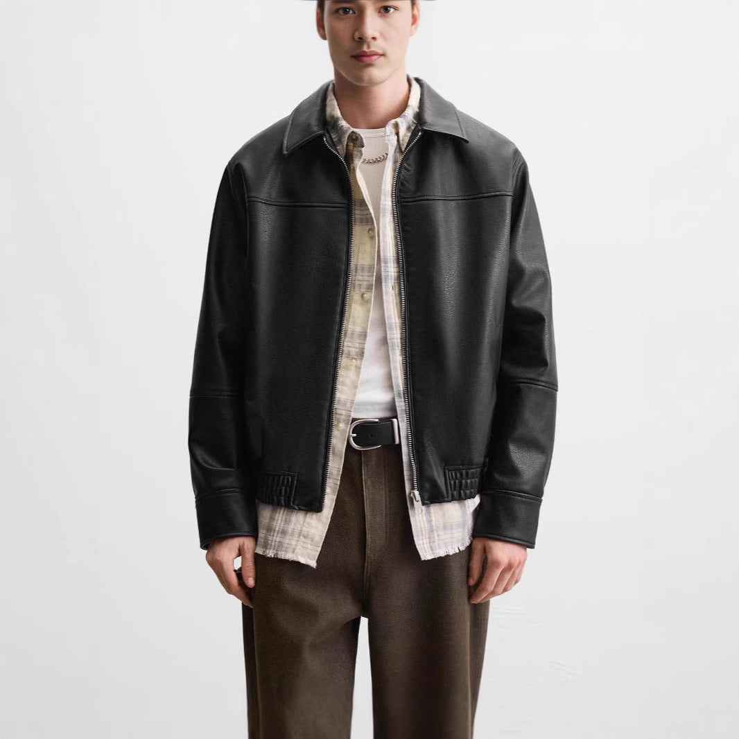 Man wearing a black leather jacket over a plaid shirt on a white background