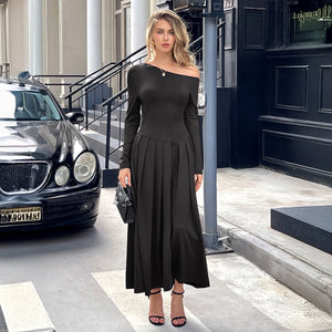 Woman in a black off-shoulder dress standing on a city street with a car and building in the background.