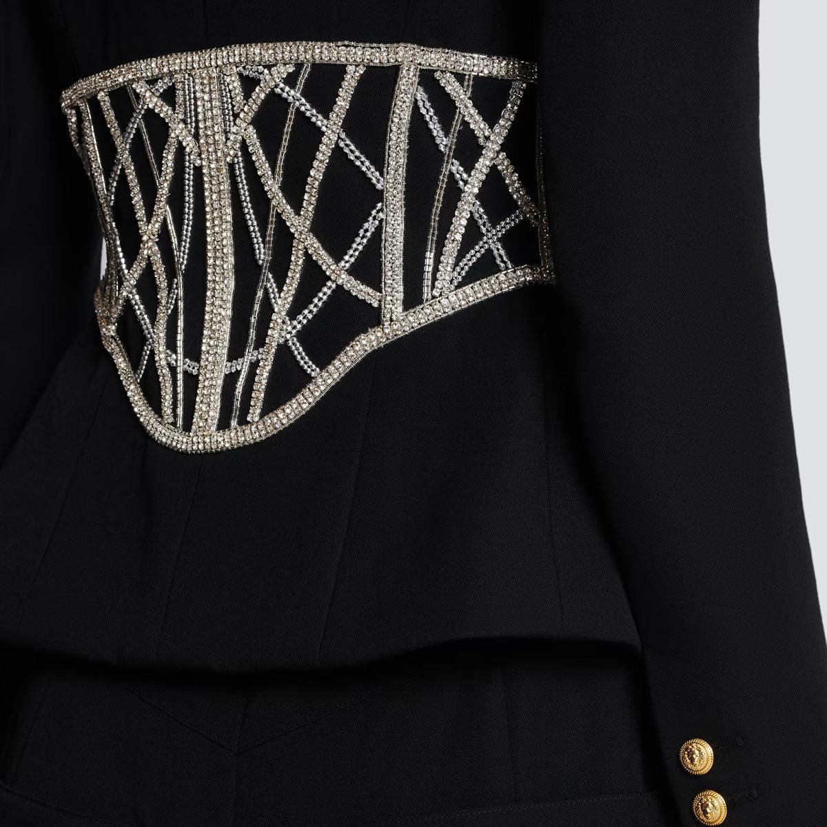 A high-end women's designer suit jacket in black with heavy beaded diamond detailing on the back.