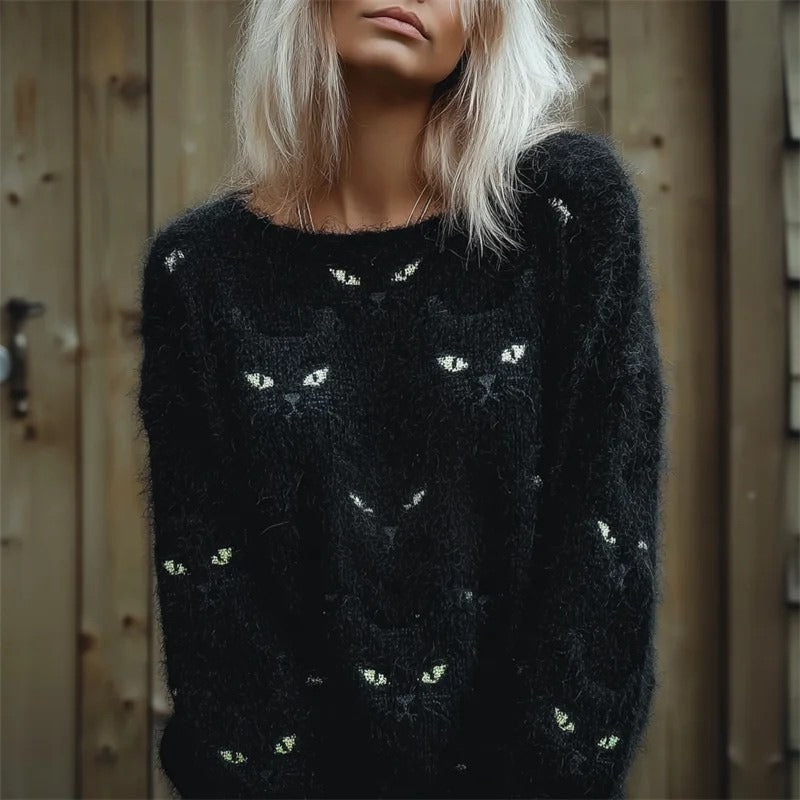 Person wearing a black sweater with cat patterns against a wooden background