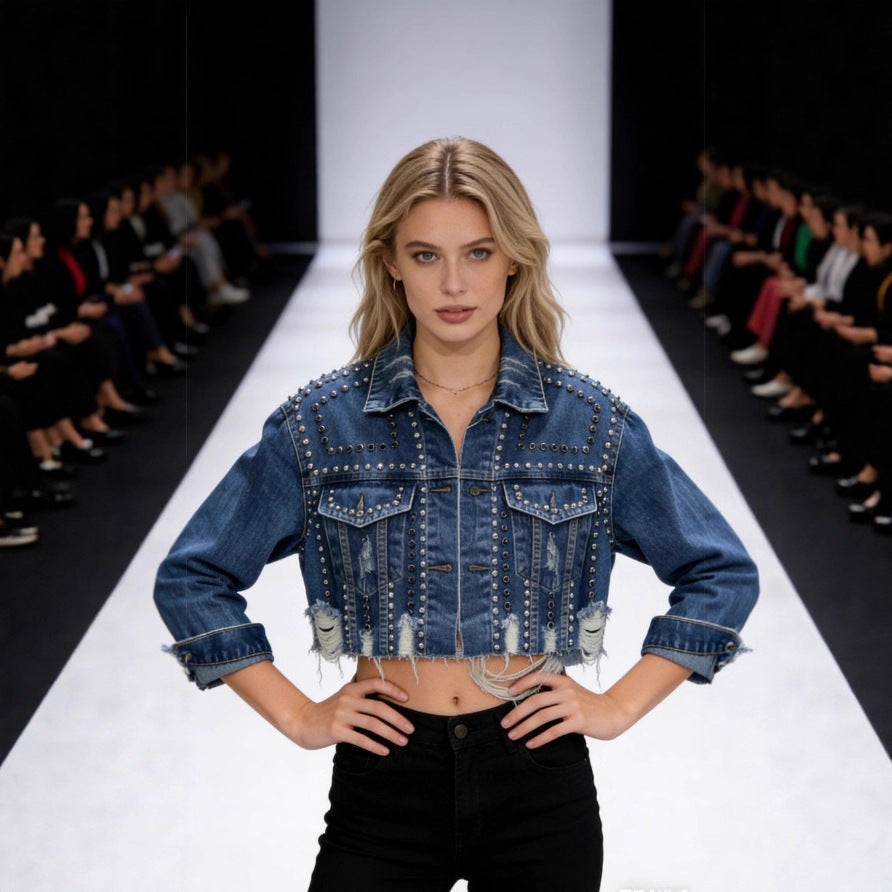 Model wearing a denim jacket on a fashion runway with an audience.