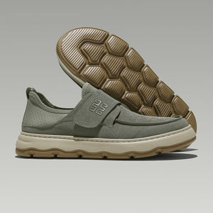 Green slip-on shoe with brown sole on a gray background