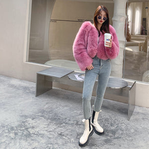 Woman in a pink fluffy coat holding a coffee cup in an urban setting.