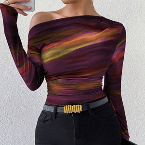 A woman wearing a long sleeve crop t-shirt with an asymmetrical neckline and a tie-dye print in apricot tones.