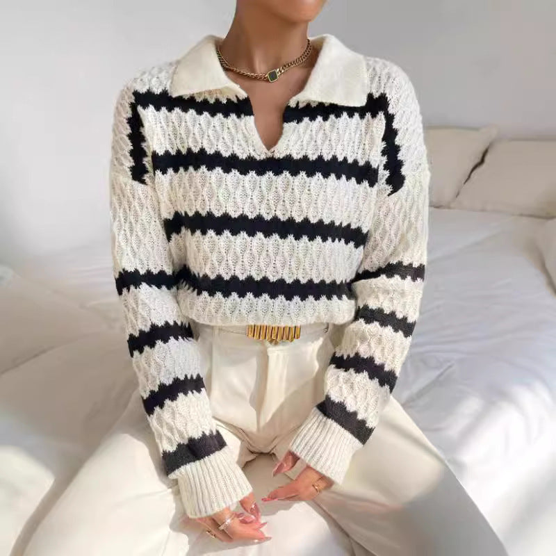Person wearing a white and black striped sweater with a neutral background