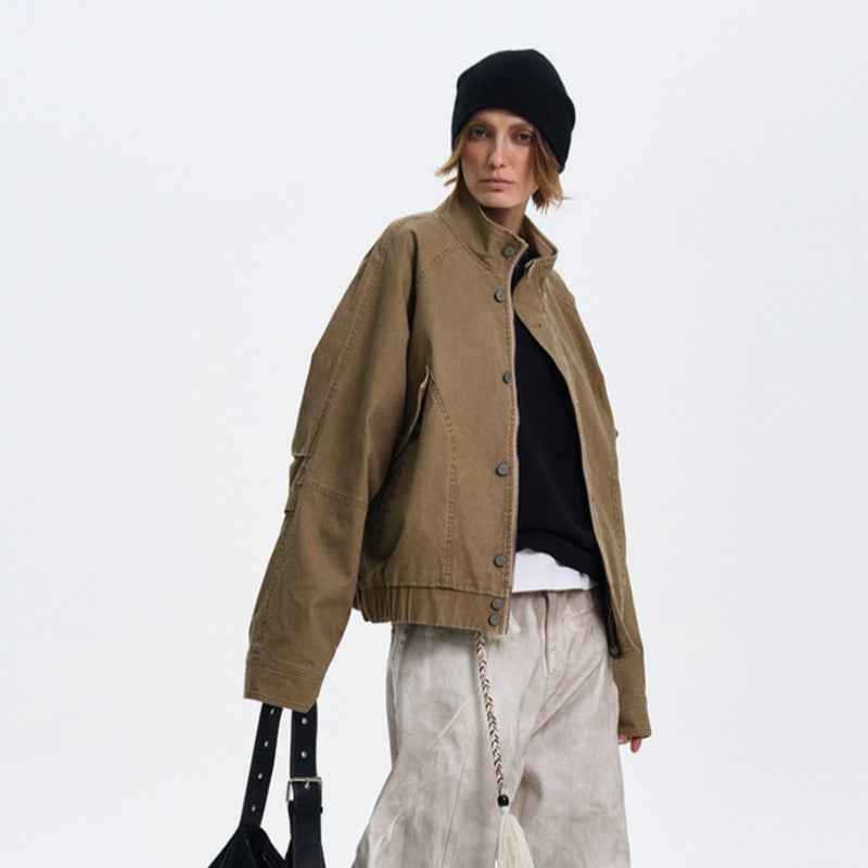 Person wearing a brown jacket, black beanie, and light pants on a white background