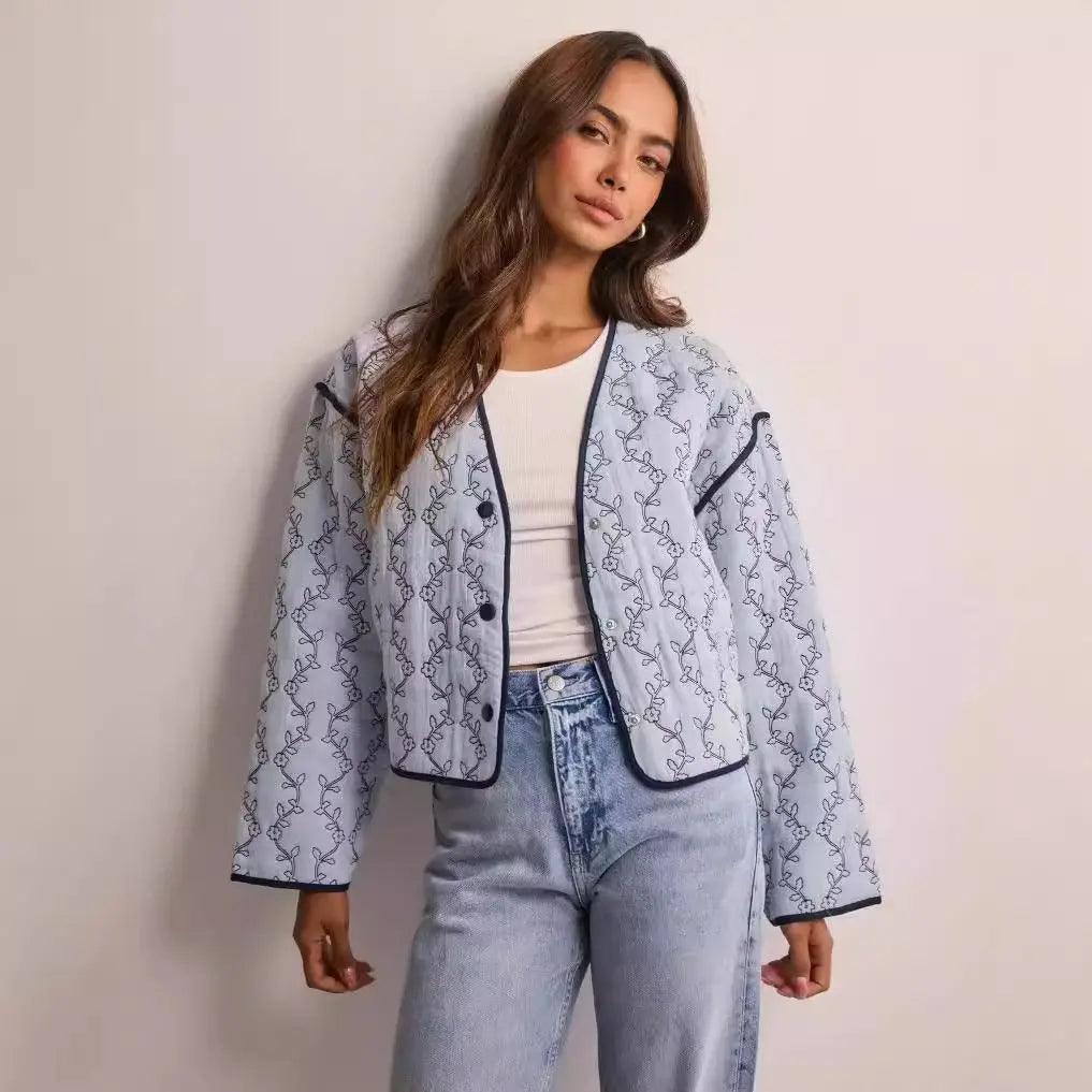 A woman wearing a blue printed jacket over a white top, paired with blue jeans.