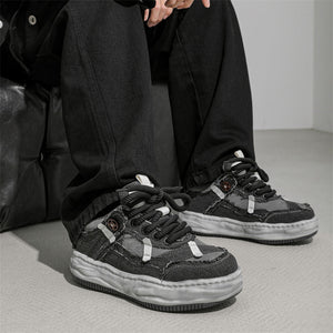 Person wearing black sneakers with a gray background