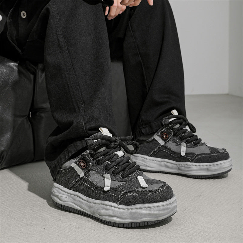 Person wearing black sneakers with a gray background