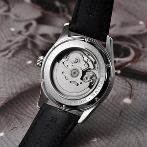 Watch with black leather strap and visible mechanical components on a textured surface