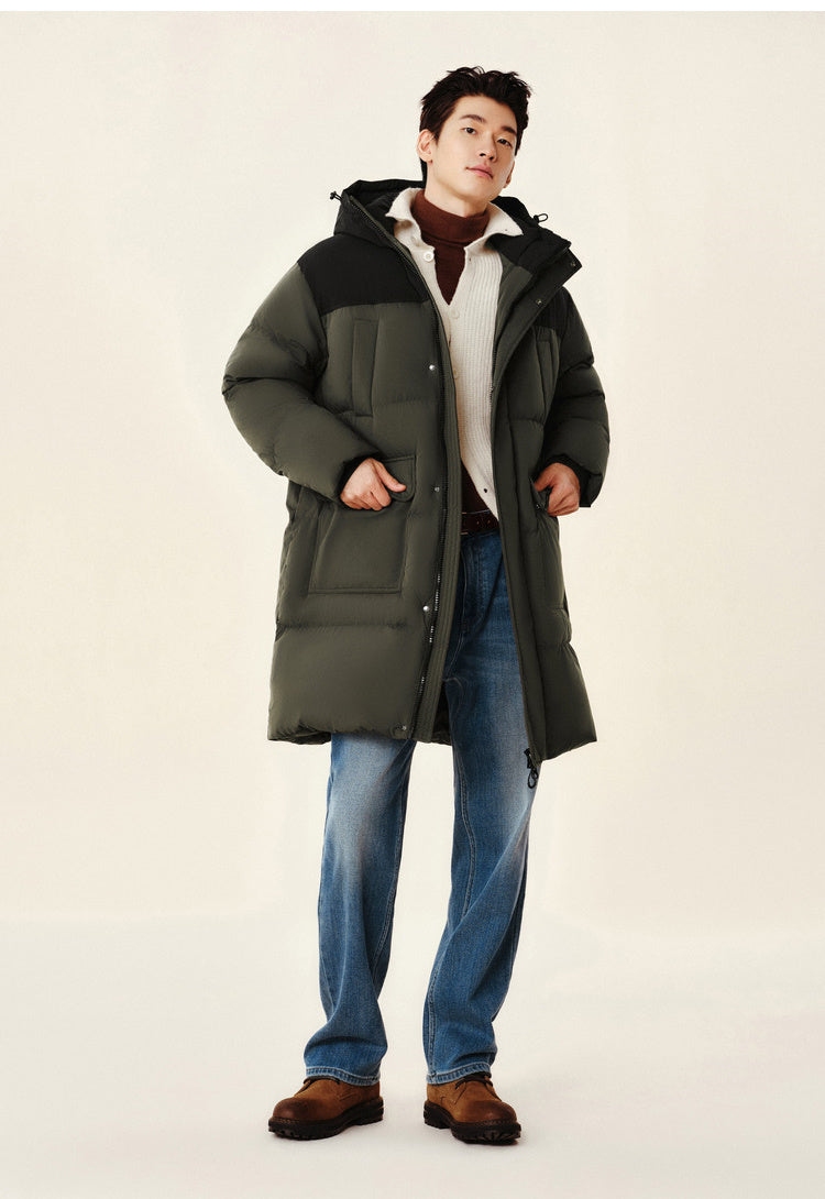 Man wearing a long green coat with a hood on a plain background