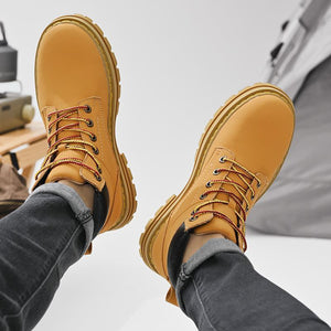Yellow work boots being worn with a neutral background