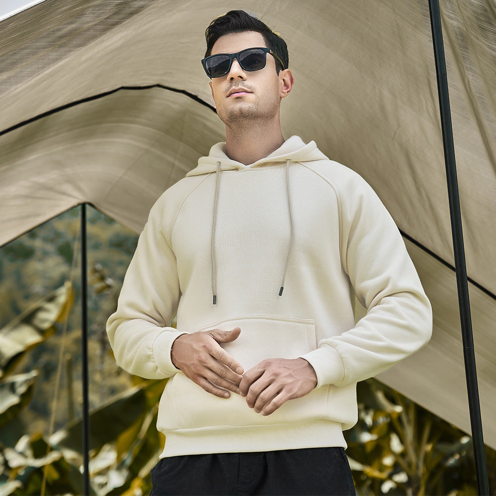 A man wearing a beige fleece hoodie with a hood, sunglasses, and standing in front of a tent.
