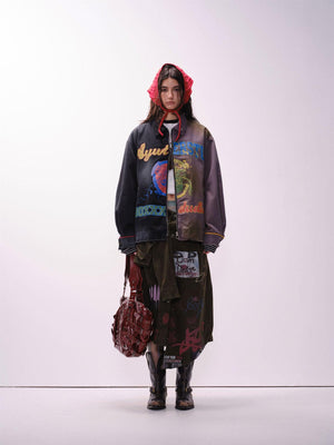 A person wearing a unisex, loose fit jacket with multicolored urban graffiti designs.