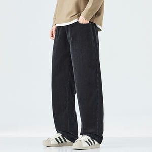 Person wearing black wide-leg pants and white sneakers with black stripes on a light gray background
