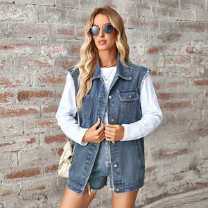 Woman wearing a denim vest over a white shirt against a brick wall.