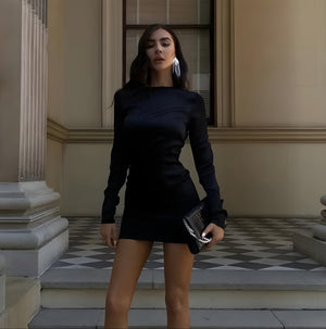 Woman in a black dress standing on steps in front of a building