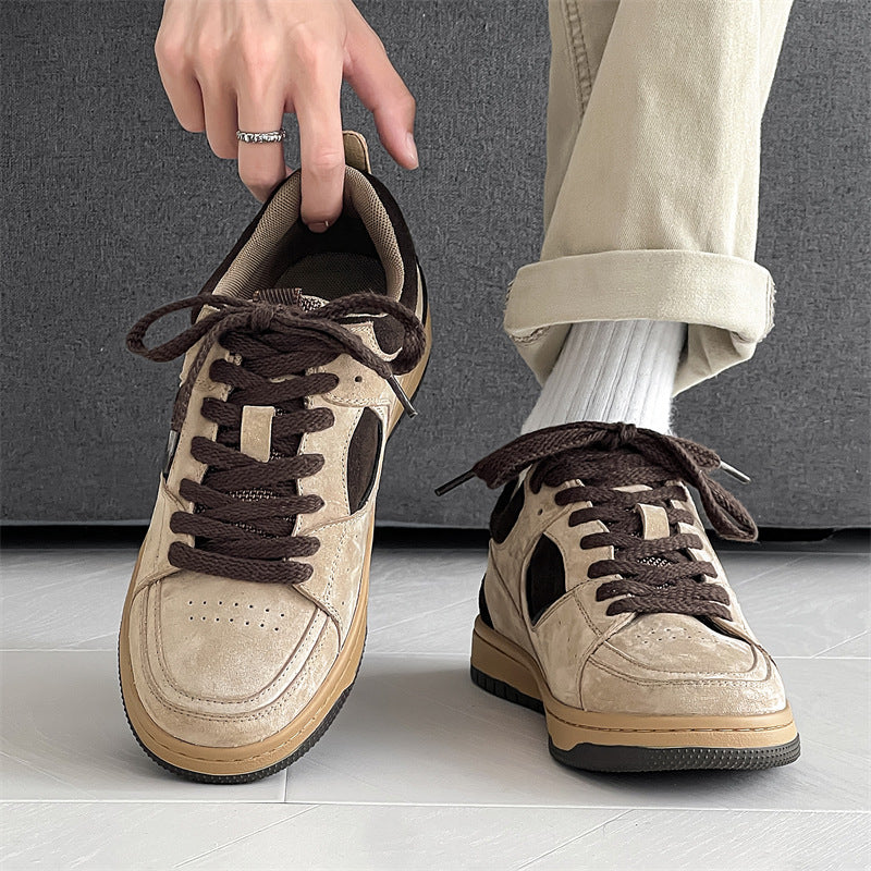 Beige sneakers with brown laces worn by a person on a gray floor.