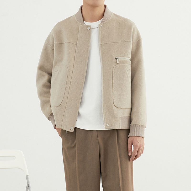 A male model wearing a beige woolen coat with long sleeves and a straight hem, paired with a white t-shirt and brown trousers.
