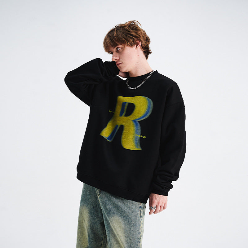 Person wearing a black sweatshirt with a large yellow 'R' on a white background