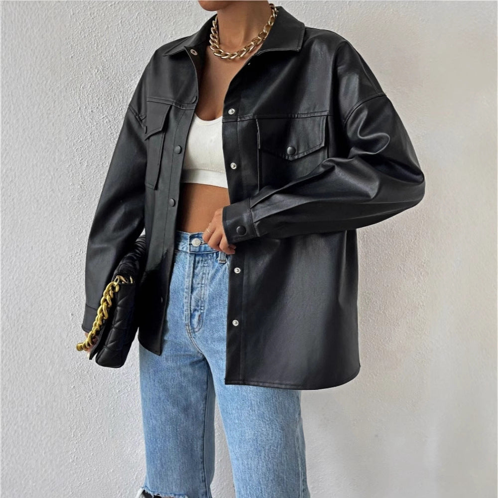 A woman wearing a black faux leather jacket with a round neckline and long sleeves, paired with a white top and blue jeans, accessorized with a chain strap bag and a gold chain necklace.