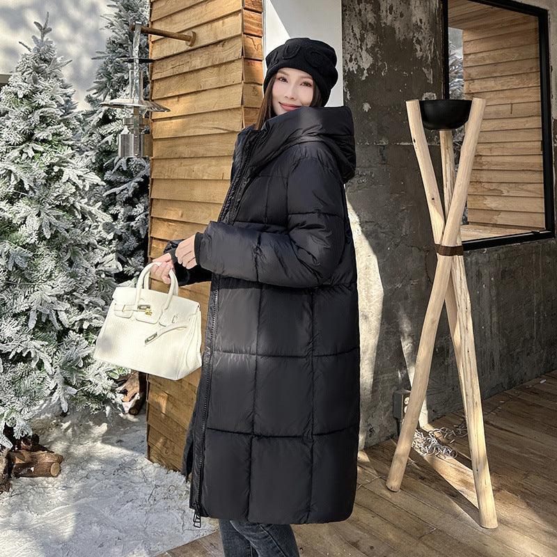 A woman wearing a mid-length hooded cotton coat in a milky white color, standing near a Christmas tree and wooden structures.