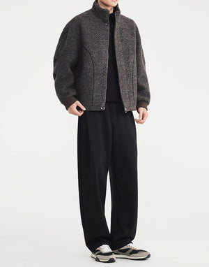 Person wearing a gray jacket and black pants on a white background