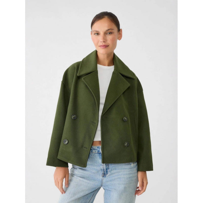 Woman wearing a green coat over a white shirt and blue jeans on a white background