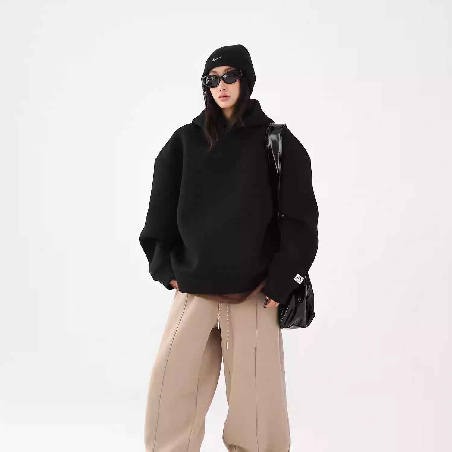 Person wearing a black hoodie and beige pants on a white background