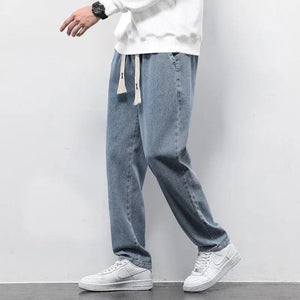 A person wearing straight-leg light blue denim jeans and white sneakers. The jeans feature a high waist and a drawstring waistband.