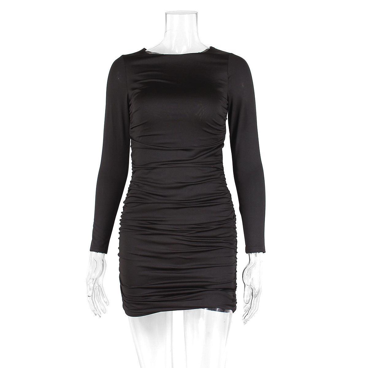 A woman wearing a black long sleeve mini dress with a round neck and backless lace-up detail.
