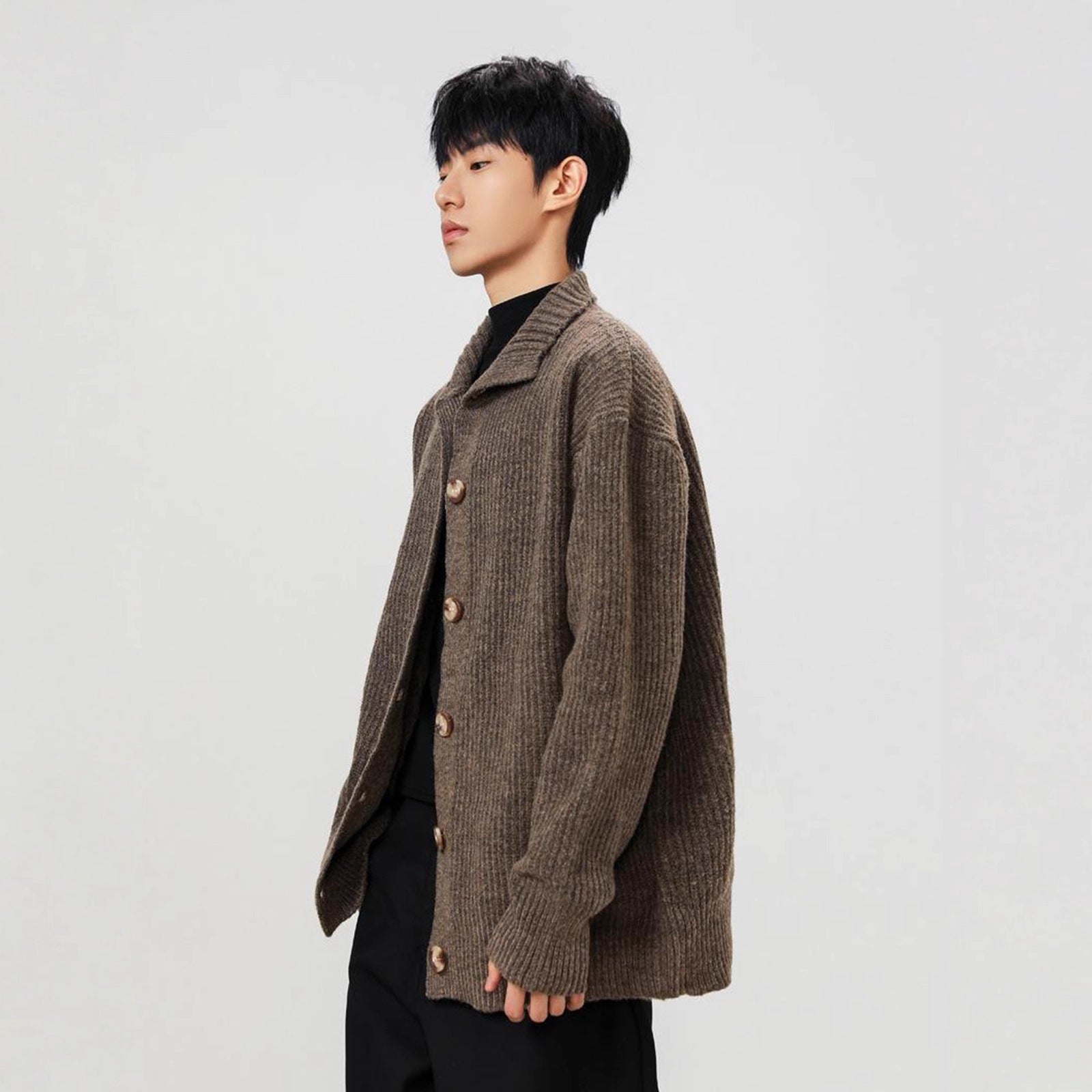 Person wearing a brown knitted cardigan on a plain background