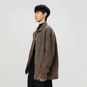 Person wearing a brown knitted cardigan on a plain background