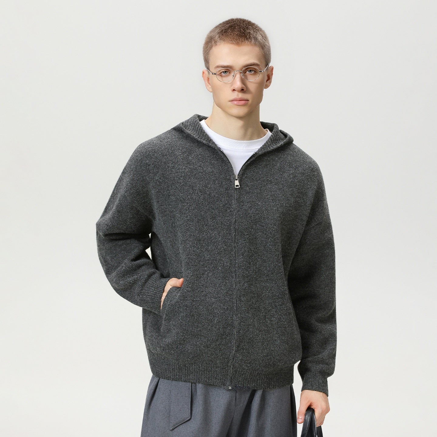 Person wearing a gray zip-up hoodie on a plain background