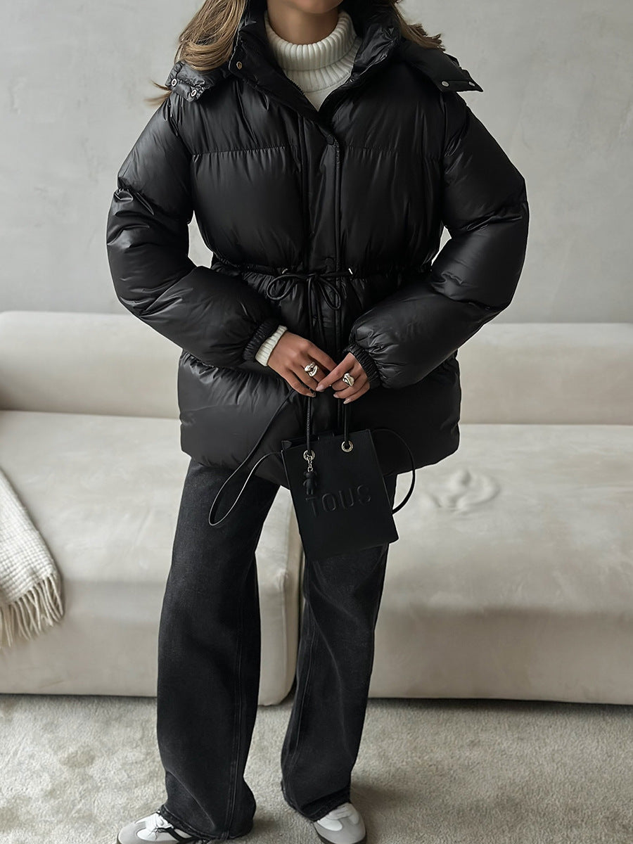 Person wearing a black puffer jacket and pants in a neutral setting