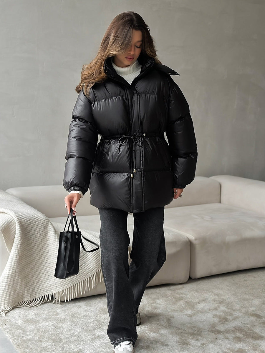 Woman wearing a black puffer jacket in a minimalistic room.
