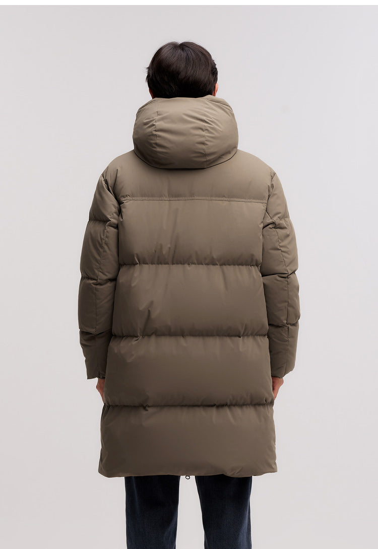 Person wearing a long brown puffer coat on a light gray background
