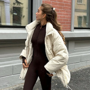 Woman wearing a white coat standing on a street with a building in the background