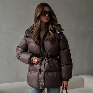 Woman wearing a brown puffer jacket against a gray background