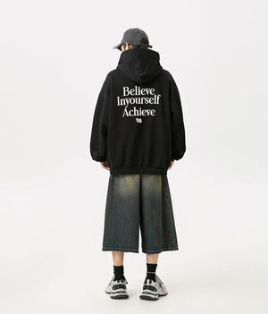 Person wearing a black hoodie with motivational text on the back, standing against a white background.