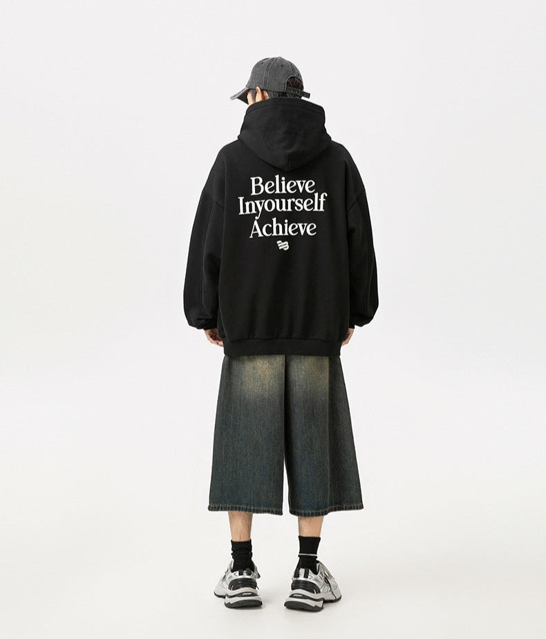 Person wearing a black hoodie with motivational text on the back, standing against a white background.