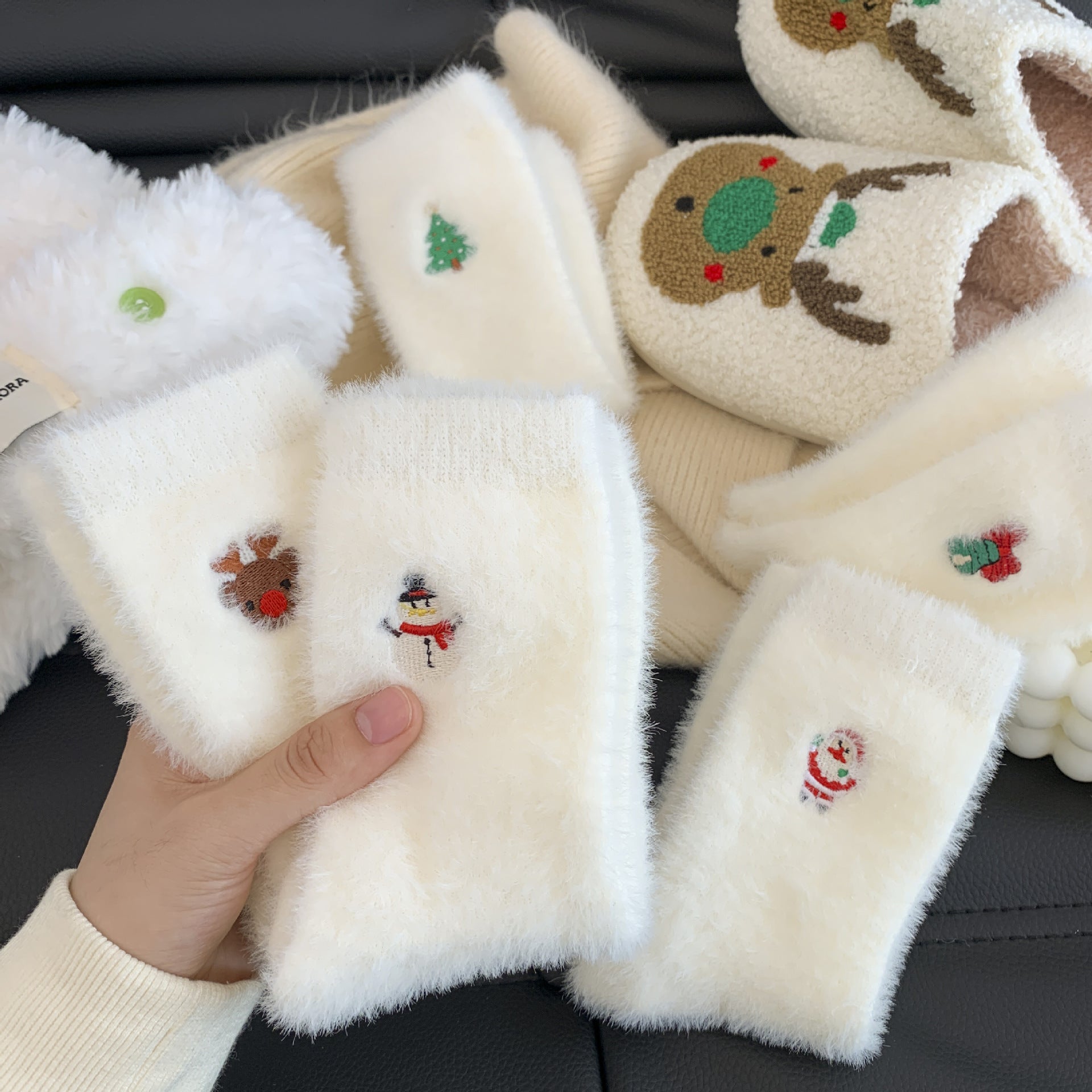 Fluffy white phone cases with Christmas-themed designs held by a hand.