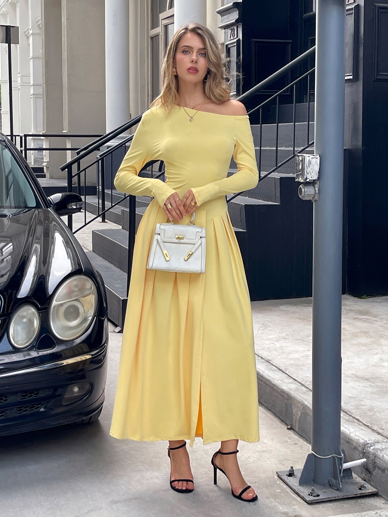 Woman in a yellow dress standing next to a car on a city street.