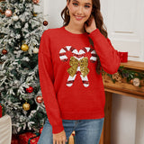 Woman wearing a red sweater with candy cane and bow design in a festive setting.